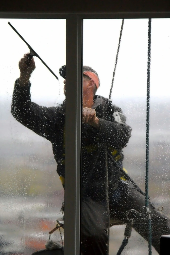 A window washer cleans a glass pane